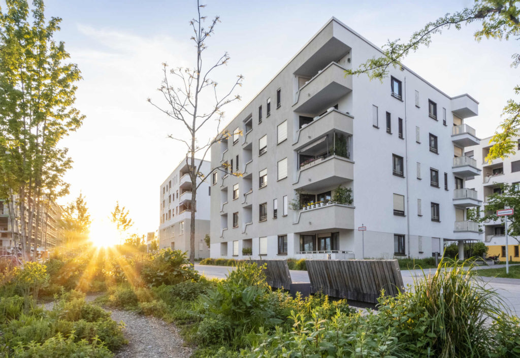 un condominio con alberi e cespugli di fronte
