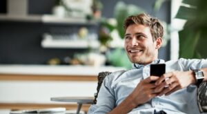 un uomo sdraiato con in mano un telefono