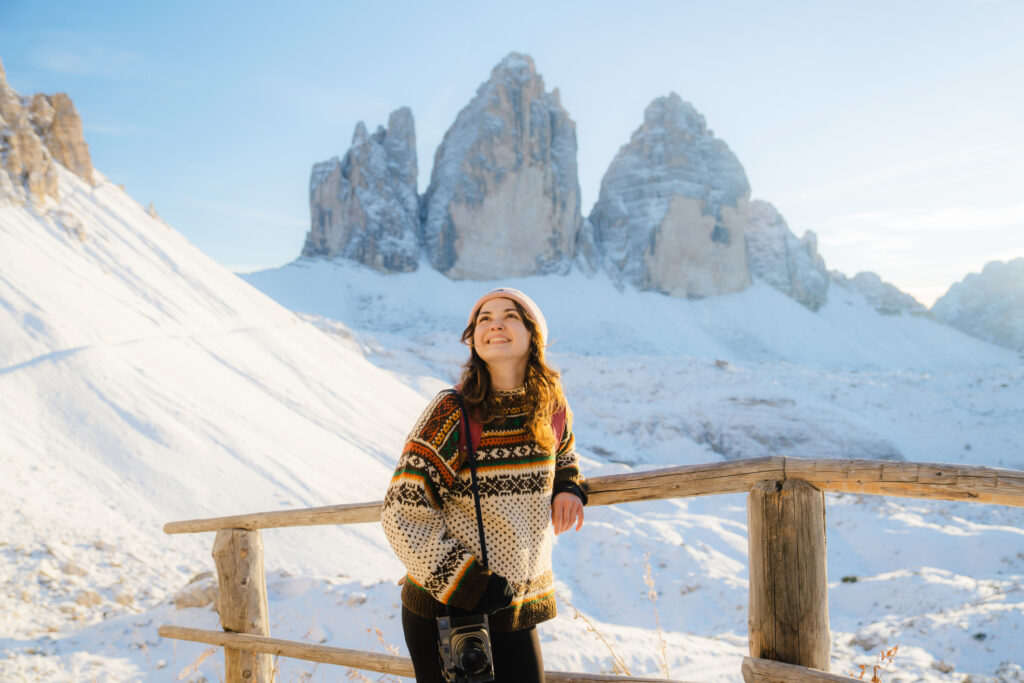 Donna con macchina fotografica sullo sfondo delle Tre Cime di Lavaredo in inverno