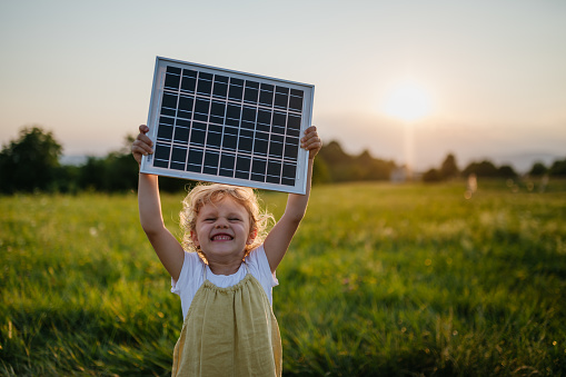 una ragazza che regge un pannello fotovoltaico