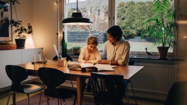 Eine Frau und ein Kind sitzen an einem Tisch und schauen sich ein Buch an