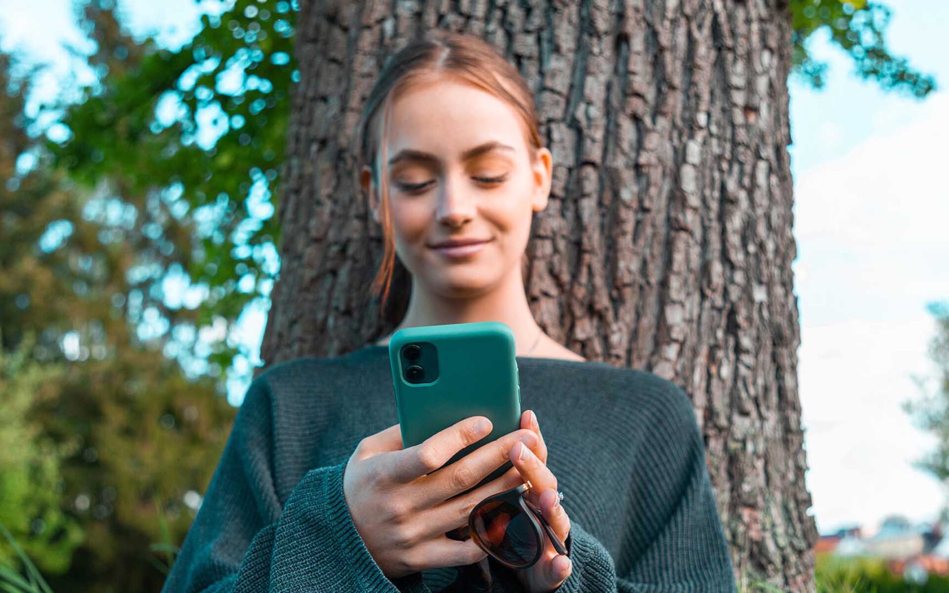 una donna che tiene in mano un telefono e sorride utilizzando un'app